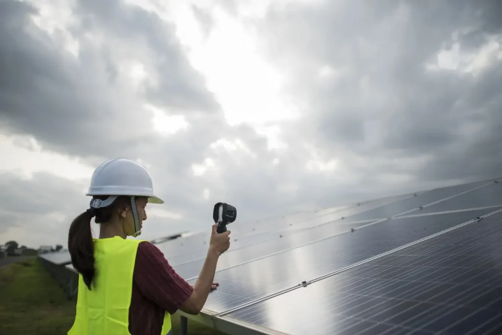 A solar installer Long Island inspecting rooftop solar panels with professional testing equipment under cloudy skies.